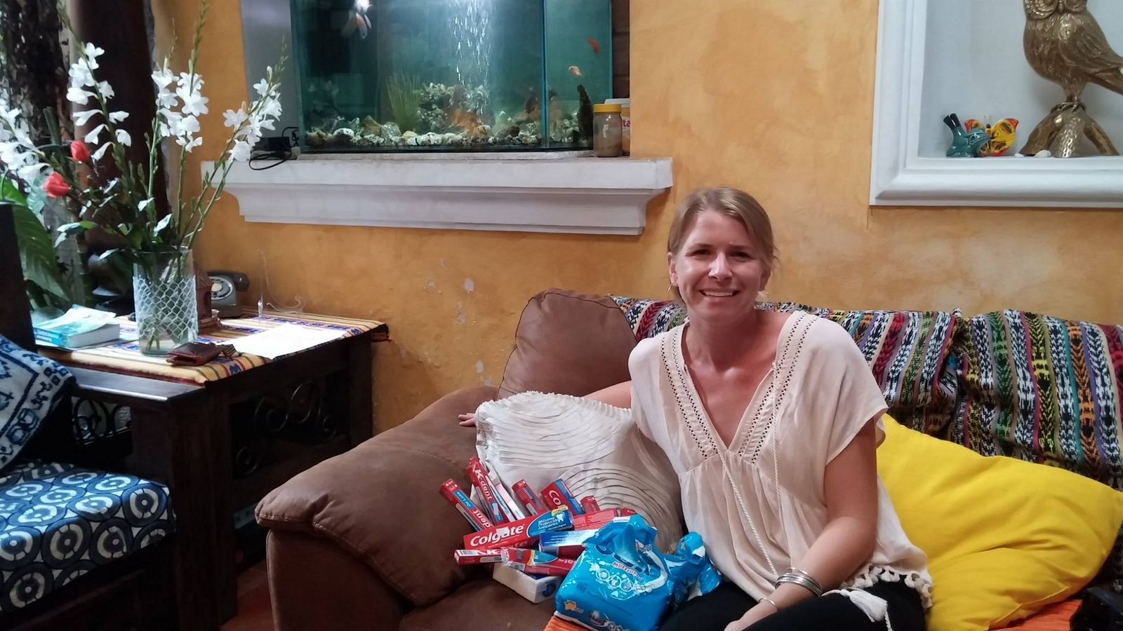 A donor on a sofa beside a pile of toothpaste and toothbrushes for the children