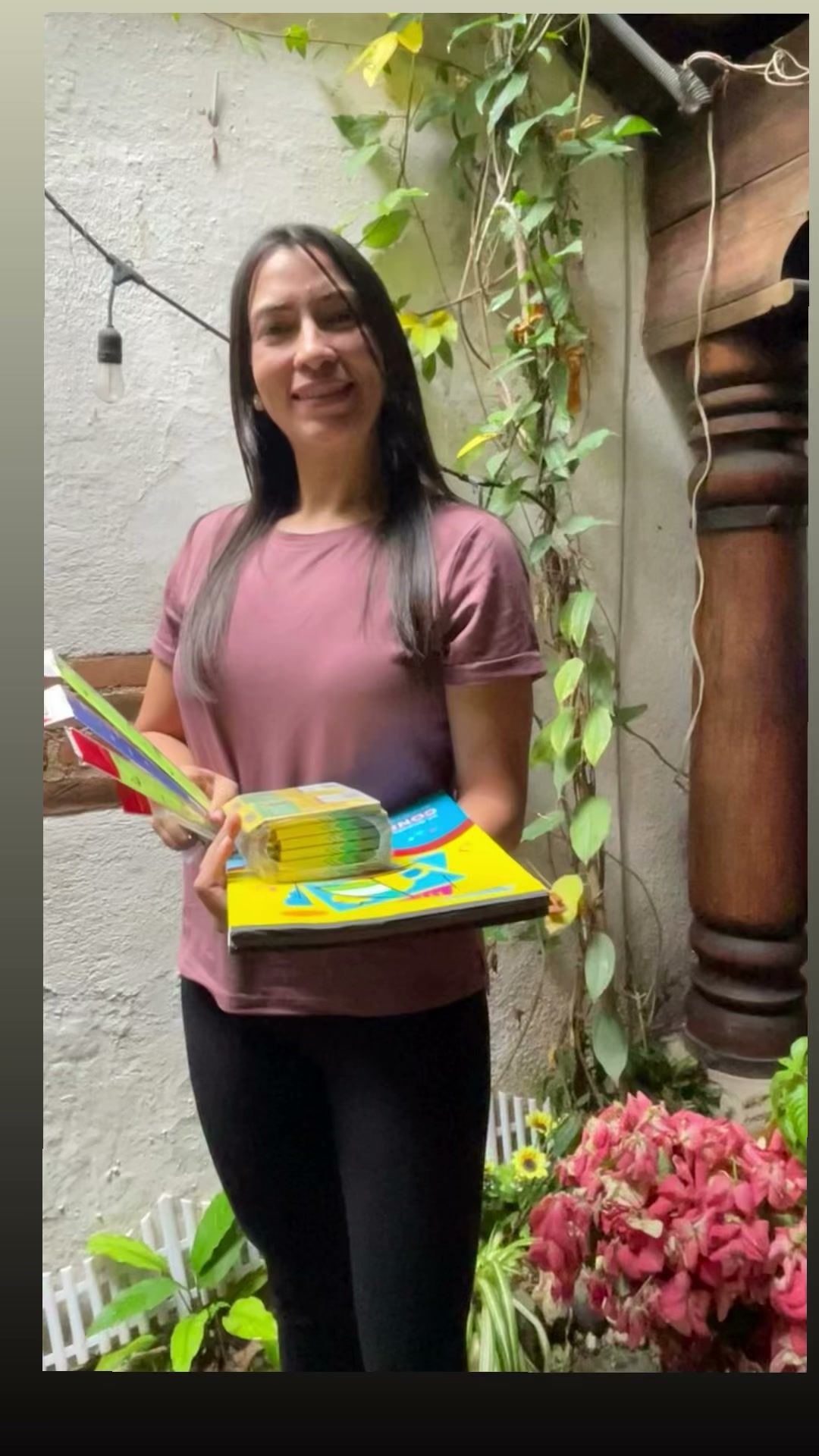 A donor smiles holding books and school supplies for the children