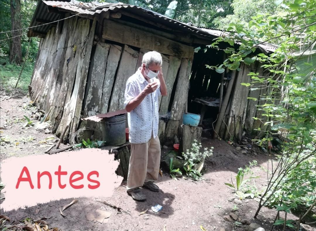 Labeled “Antes” (before): an older man in a face mask stands in front of a worn plank house with a rusty roof