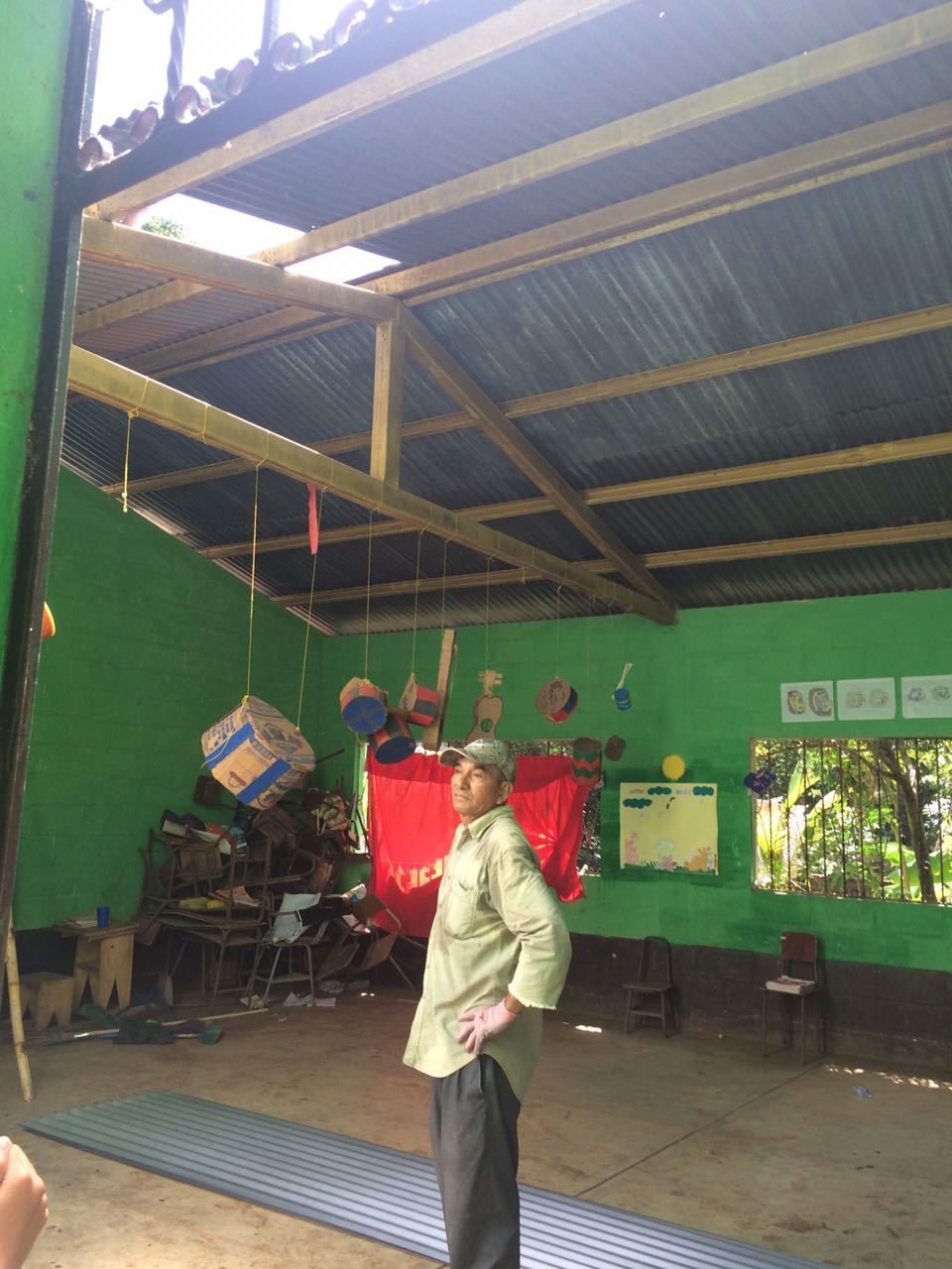 A man inspects the metal roof of a green classroom at the Las Delicias school, a new sheet on the floor