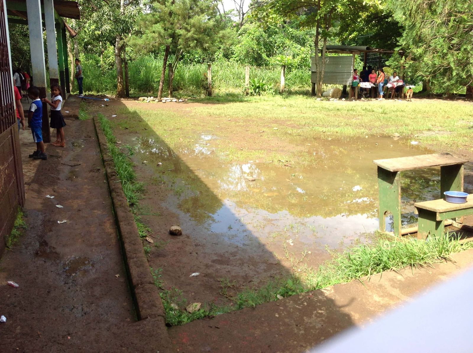 The courtyard of the Las Delicias school flooded after rain, with a wooden desk standing by the water