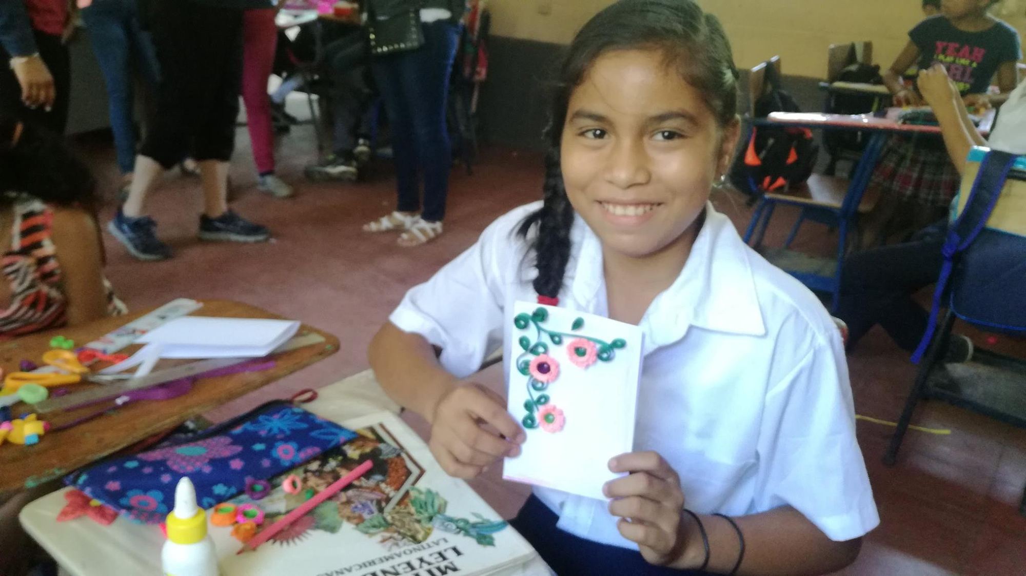 A schoolgirl shows the card with rolled paper flowers she made during a February school visit