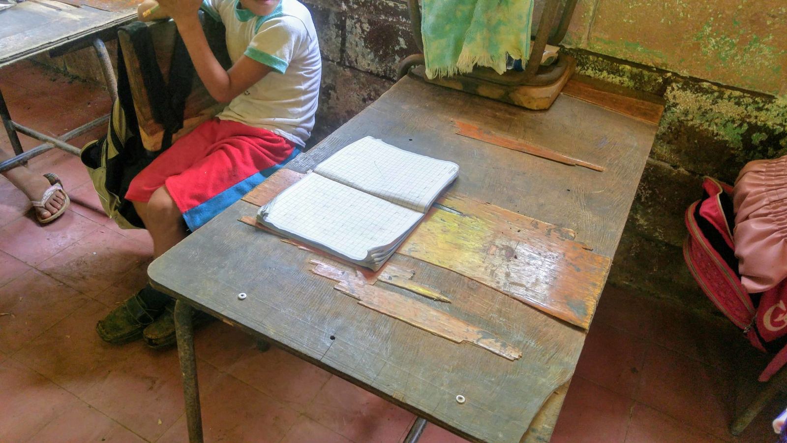 A broken, weathered wooden school desk with an open notebook on top