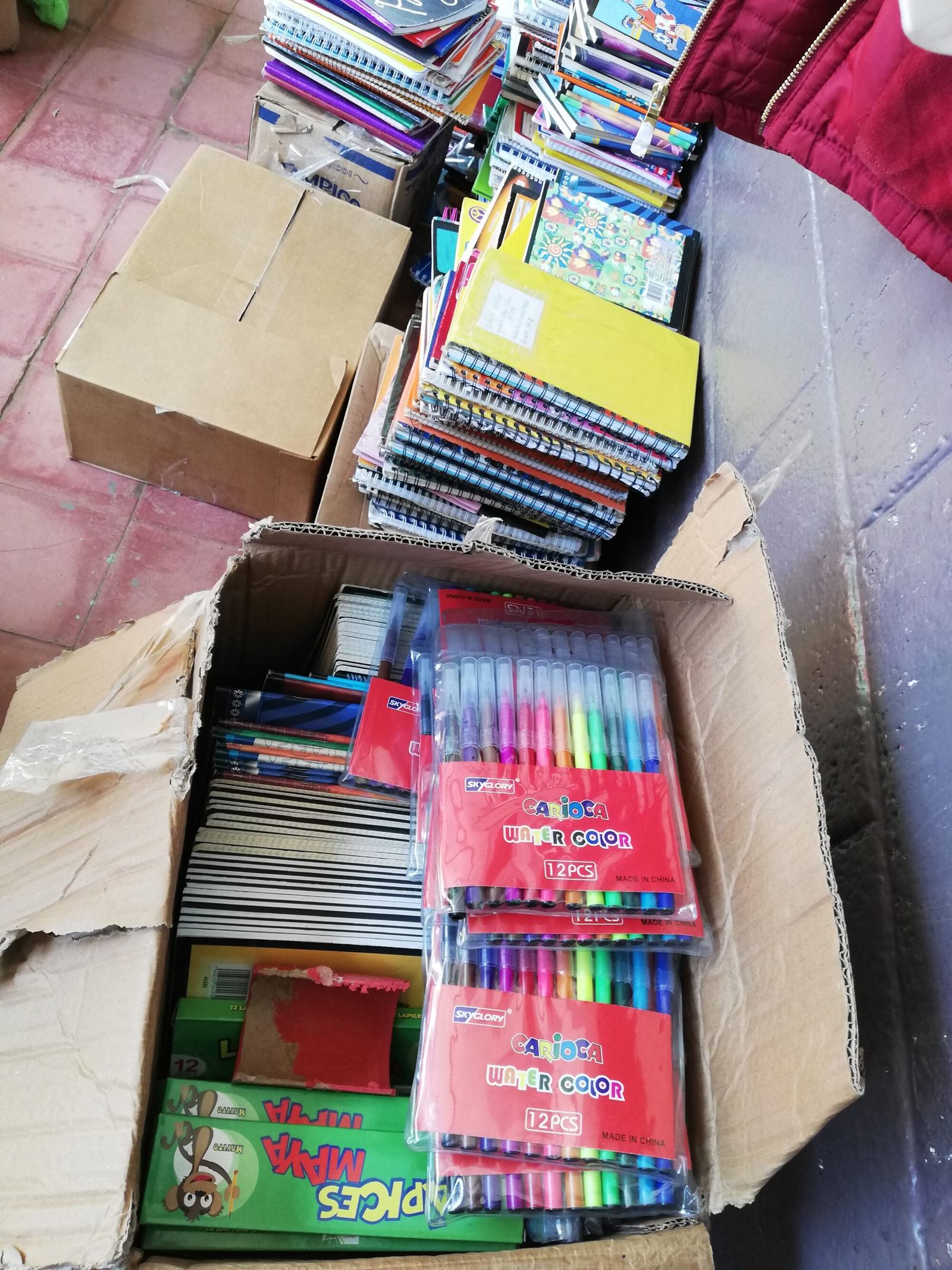 Open boxes of notebooks and markers ready to be handed out at the school