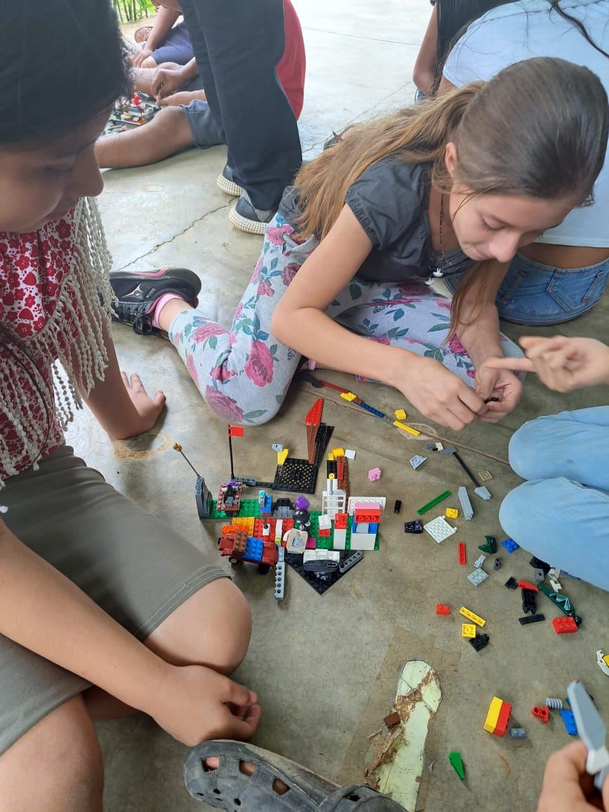 Children sitting on the floor build structures with colorful plastic building blocks