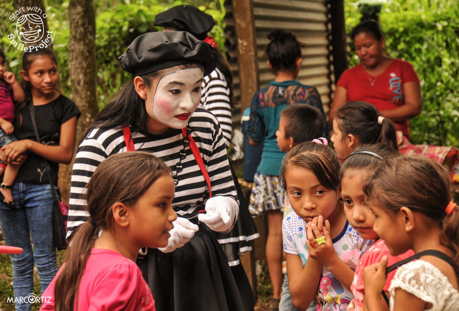 A young woman dressed as a mime chats with a group of girls at the Children’s Day party in Las Delicias del Jobo