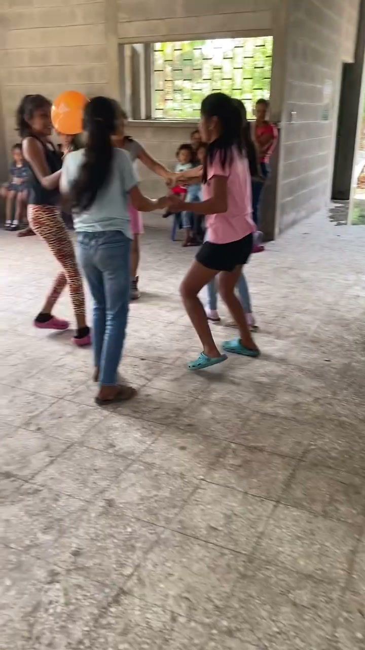 Girls dance in a circle with a balloon during a games day