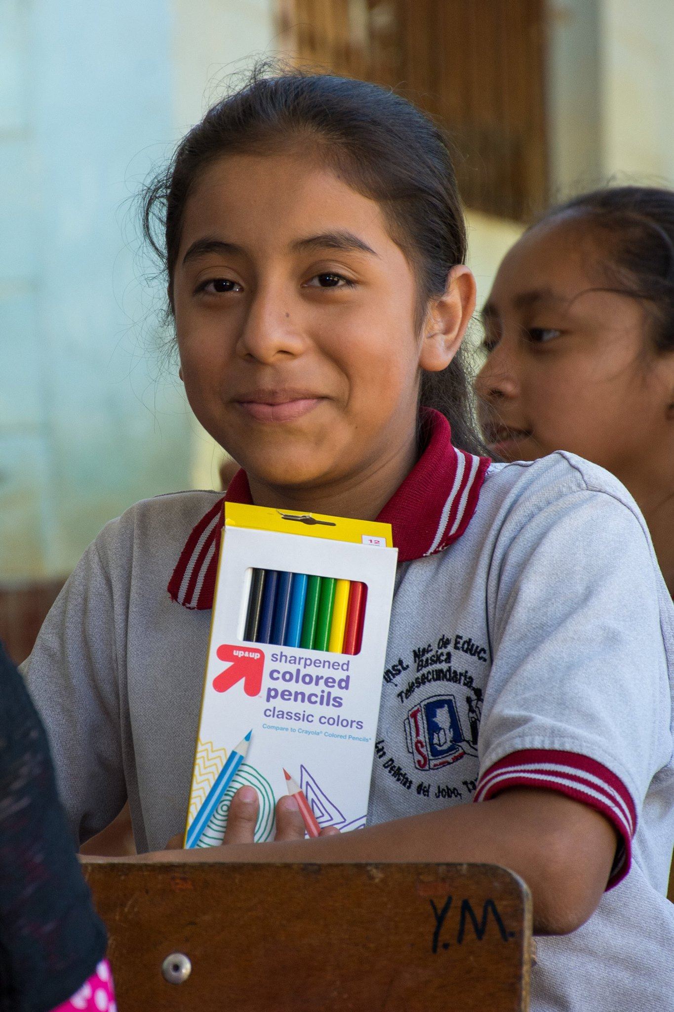 A secondary student in Las Delicias del Jobo smiles with the box of colored pencils she received